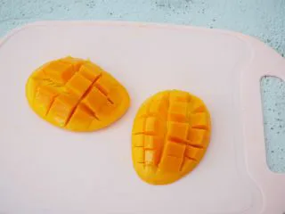 芒果酸奶吐司,芒果芒果核为中心，在果核右边切一刀，芒果被分为两部分，取芒果果肉上划格子，但是注意不要切到皮，把划好格子的芒果拿在手上，手指抵住芒果皮往上顶，再用刀切出果肉即可