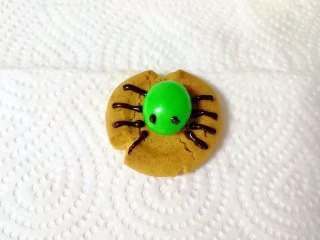 万圣节蜘蛛饼干,继续用裱花袋画出蜘蛛的眼睛和腿，一个萌萌的蜘蛛饼干完成了。