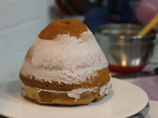 圣诞树枫糖戚风, 脱模后的戚风蛋糕分成4片，夹层抹奶油，抹厚一些。喜欢水果的可以加新鲜水果。每盖上一层蛋糕片之后要轻轻按压使上下蛋糕片贴合紧密。全部组装好之后用抹刀把挤压出的多余奶油涂抹在蛋糕体表面 