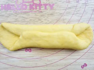 南瓜椰蓉面包条,取一个团子擀开成椭圆形横放对折 