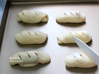 脆皮肠小面包,拿走保鲜膜，用刀在面包表面划三道痕，划刀要锋利一点，不要来回拉扯面包，否则面包会变形，不好看；