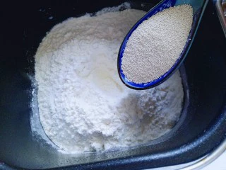 #甜味#毛毛虫豆沙面包,加入高筋面粉，奶粉，再面粉的顶端挖个小洞，(注意不要挖到液体) 然后把酵母粉倒入挖好的小洞里。