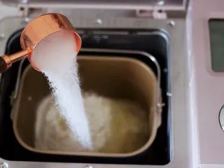 海虾杂蔬披萨,首先把面粉加入面包机里,把酵母用温水化开后,再分次倒入白砂糖和盐。