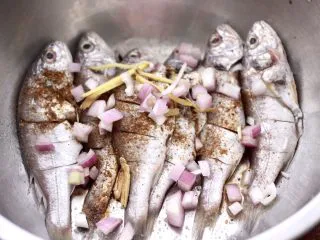 香辣孜然烤鱼,把切碎的洋葱和姜丝倒入盆里，用手抓匀后腌制30分钟。