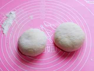 披萨新吃法~奥尔良鸡丁披萨,发酵好的面团取出,分成2份,盖上湿布揉圆醒发10分钟。