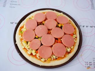 杂蔬火腿肠披萨,再放入胡萝卜、玉米粒、青椒、火腿片