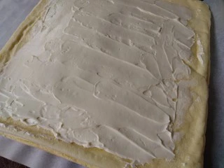 圣诞树根蛋糕,切去蛋糕的四条边,将打发好的淡奶油抹在蛋糕上