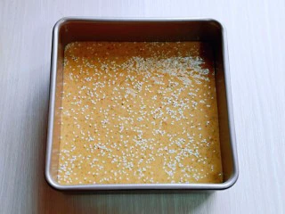 红糖枣糕别在外面买了~自己在家做~健康无添加,拌好的红枣枣泥糊倒入模具中,用刮刀刮平整,轻轻震几下,将气泡震出,再撒上白芝麻。