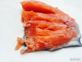 秘制干煎三文鱼 ,用刀将它横向切，切成条，注意鱼皮不要切断。