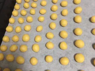 扁桃仁一口酥,烤盘里铺上油纸,如果是不沾烤盘就不用油纸,我家不沾小烤盘装不下,所以用了大的,两手揪成小粒,搓圆后放入烤盘中,时间不能太长要快