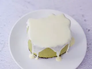 4寸KT猫抹茶慕斯蛋糕,把白色巧克力隔水融化,然后慢慢淋上慕斯蛋糕表面,放入冰箱冷藏备用