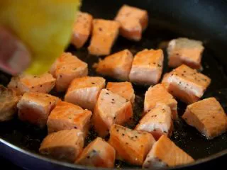 双椒土豆三文鱼,煎到一面上色微黄翻面，再撒些黑胡椒碎和盐，挤些柠檬汁，晃晃锅，同样微黄上色就可盛出备用。 注：两面微上色就可，内部如有点红丝没有关系，因为三文鱼块自身还有热量，待到你整个烹饪过程结束后就熟透了，且不可煎的时间过长，否则口感就不水嫩了。