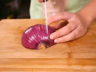 法式香橙煎鸭胸 , 洋葱去掉外皮后洗净,洋葱的切面朝下放在砧板上,垂直向下切开。