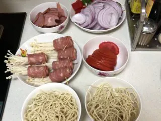 西餐菲力牛排,将食材切片，培根包好金针菇的同时可以先将清水煮开后放入热干面烫至1.5分钟左右后用平底锅小火煎至培根金针菇至熟