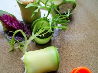 黄花鱼遇上西餐,把黄花鱼卷和黄瓜卷以及苦苣放在盘子中。