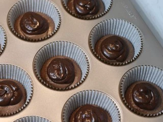 巧克力熔岩杯子蛋糕,将甘纳许装入裱花袋后挤在蛋糕糊中间(甘纳许挤多少没有要求,喜欢满满巧克力的可以多挤些。不过最好确保甘纳许不会挤到底部面糊边缘。甘纳许要和面糊边缘有一些空间)