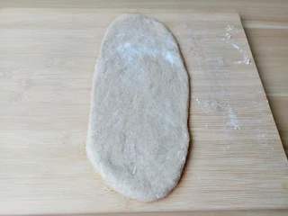 黑麦全麦吐司,用手把面团里的气体挤压出来，把面团分成三份，放在室温下中间发酵15分钟。取1个面团在案板上擀成长椭圆形。