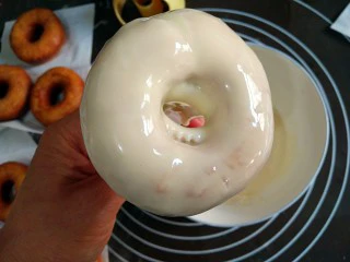 巧克力甜甜圈,这里需要注意的是,甜甜圈翻过来时要迅速,不然会出现“滴泪”(流到背面)的情况,同时用拇指和小指轻轻捏住并微微晃动,让巧克力在上面呈现出均匀的状态。