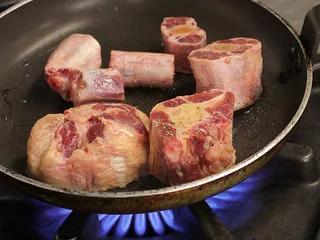 番茄红酒烩牛尾,平底锅烧热，倒入少许油，将调好味道的牛尾两面略煎上色，封住牛尾的肉汁