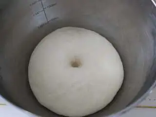 自制培根披萨,搭湿布,将面盆放置温暖处进行发酵。当面团发酵至两倍大时,用手指沾面粉,轻轻地在面条上扎个洞,面团不回缩、不塌陷即可。