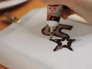 红丝绒蛋糕 无需酪乳 奶酪霜抹面,根据蛋糕的尺寸，把logo画出来。 用ps把logo画一下，把图片传到pad。 烘焙纸夹在平板上，巧克力笔一会就凝固了，笔头挺粗的，画不了太精细的，所以要用镜像的图案。 室温静置几分钟，就可以把巧克力取下。