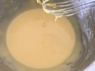 戚风杯子蛋糕,首先准备好一个容器，里面倒入牛奶和玉米油搅拌乳化好，过筛低筋面粉和玉米淀粉进去，搅拌混合好再加入蛋黄，继续搅拌成细腻的状态备用。