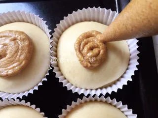 奶香咖啡面包,面包发酵至有原来的两倍大以后，将咖啡面糊装入裱花袋，在裱花袋前端减一个大小合适的孔，然后把面糊以画圈的方式，挤在面团表面，不用挤满，覆盖表面的二分之一就可以了