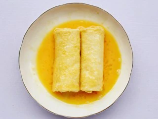 爆浆芝士火腿土司卷,卷好的土司卷,放到蛋液中滚一下。