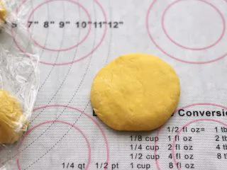 南瓜酸奶华夫饼,盖保鲜膜松弛10分钟后，取一个面团摁扁。