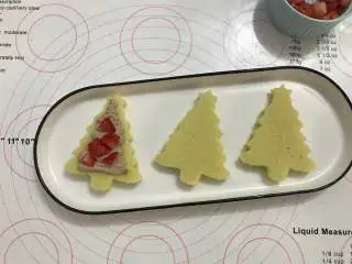 迷你圣诞树蛋糕,取一片蛋糕片，挤上奶油，放上草莓，再挤上一层奶油，盖上另一片蛋糕片。