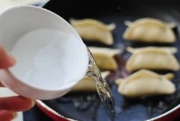 鲜肉韭菜锅贴,倒入半碗清水,盖上锅盖继续煎。
