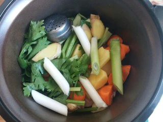 羊肉胡萝卜土豆滋补暖身汤,葱段、姜片放入锅胆里,再将八角等香料装入调料盒里一同放入锅胆里