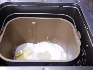 香葱芝士面包,把主配方所有材料按照先液体再粉末的顺序放进面包桶内，黄油放一侧，选择面包机发面程序。