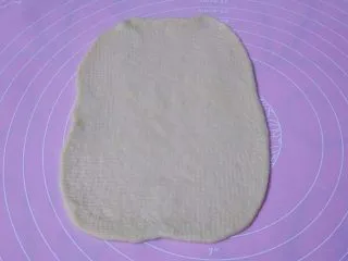 香葱芝士面包,取一个面团擀成长方形，松弛过的面团比较容易擀，觉得不太好擀的可以换一面再擀平，宽度不要太长，以超出火腿肠1-2厘米最合适