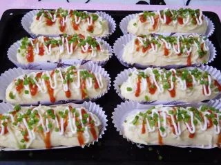 香葱芝士面包,依次撒上马苏里拉奶酪，挤上番茄酱，沙拉酱，撒一点香葱叶，就可以进烤箱了