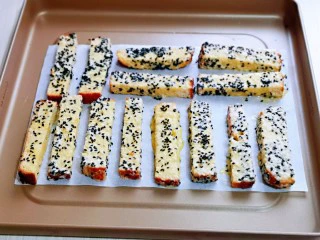 简单快手小零食～黑芝麻椰香吐司条,依次做完的吐司条，摆放垫油纸的烤盘中，并间隔距离。